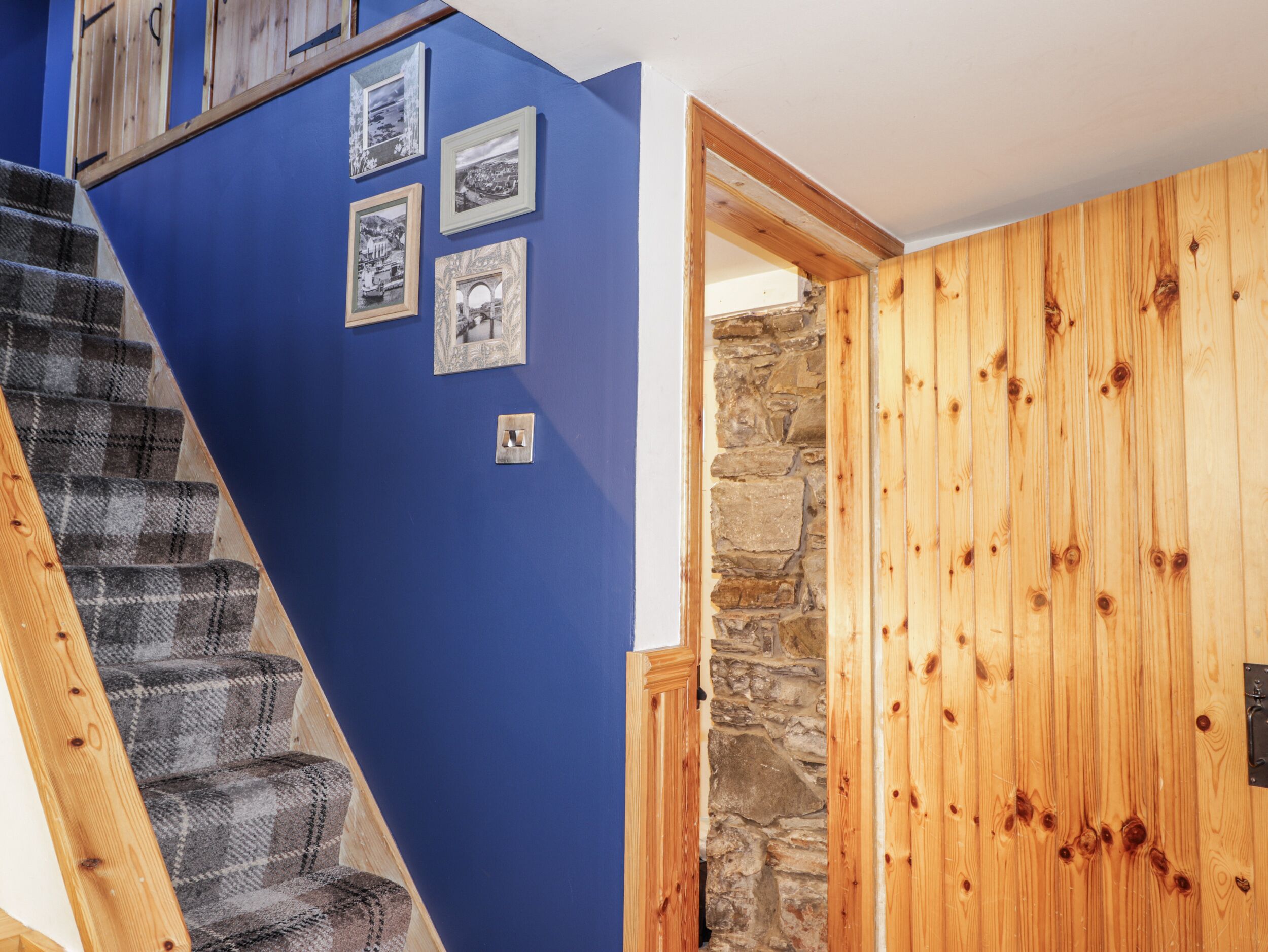 A staircase with a blue wall, wooden door, and stone wall.