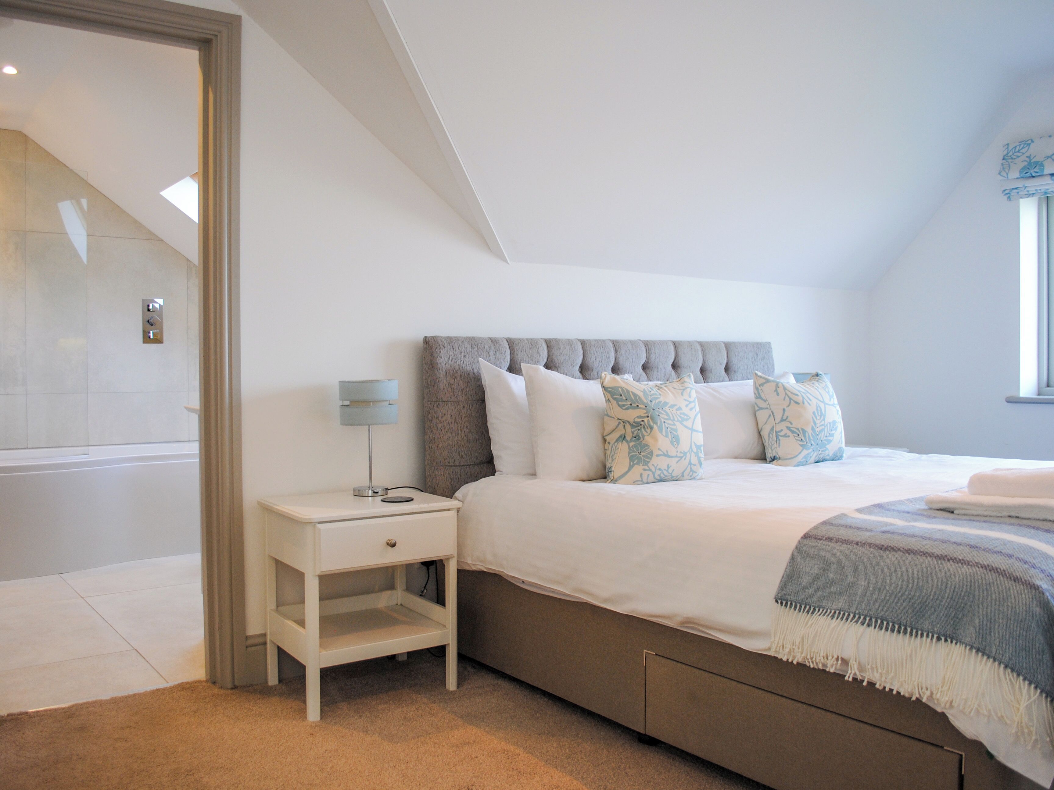A bedroom with a bed, bedside table, and a window.