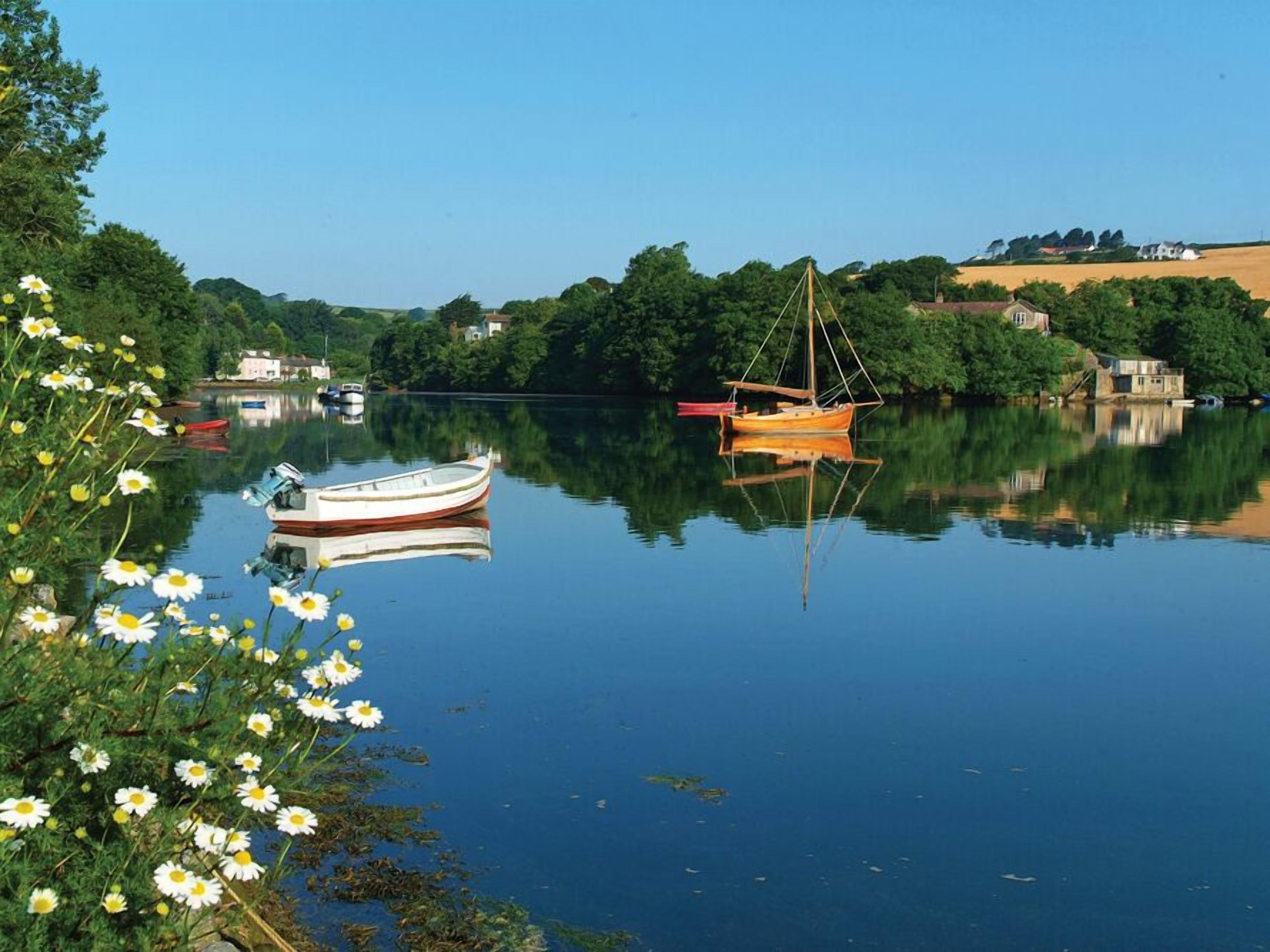 A calm river with boats and greenery.