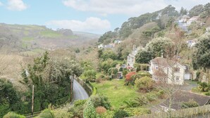 A rural landscape with houses on a hillside, a winding road, and lush greenery. - 1 Hazeldene (Salcombe)