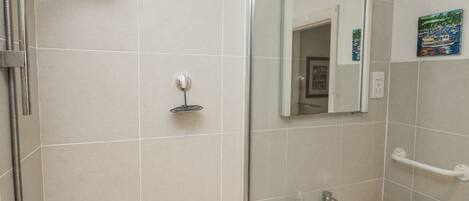 A bathroom with a shower, a sink, and a mirror.