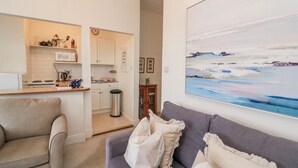 A living room with a grey sofa, a beige armchair, and a painting of a seascape. - 1 Hazeldene (Salcombe)