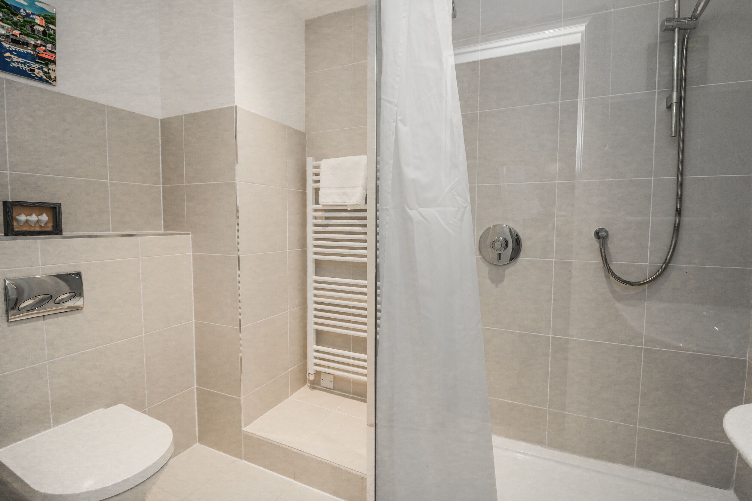 A modern bathroom with a shower, toilet, and a towel rack.