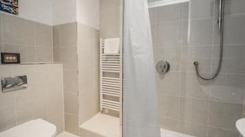 A modern bathroom with a shower, toilet, and a towel rack.