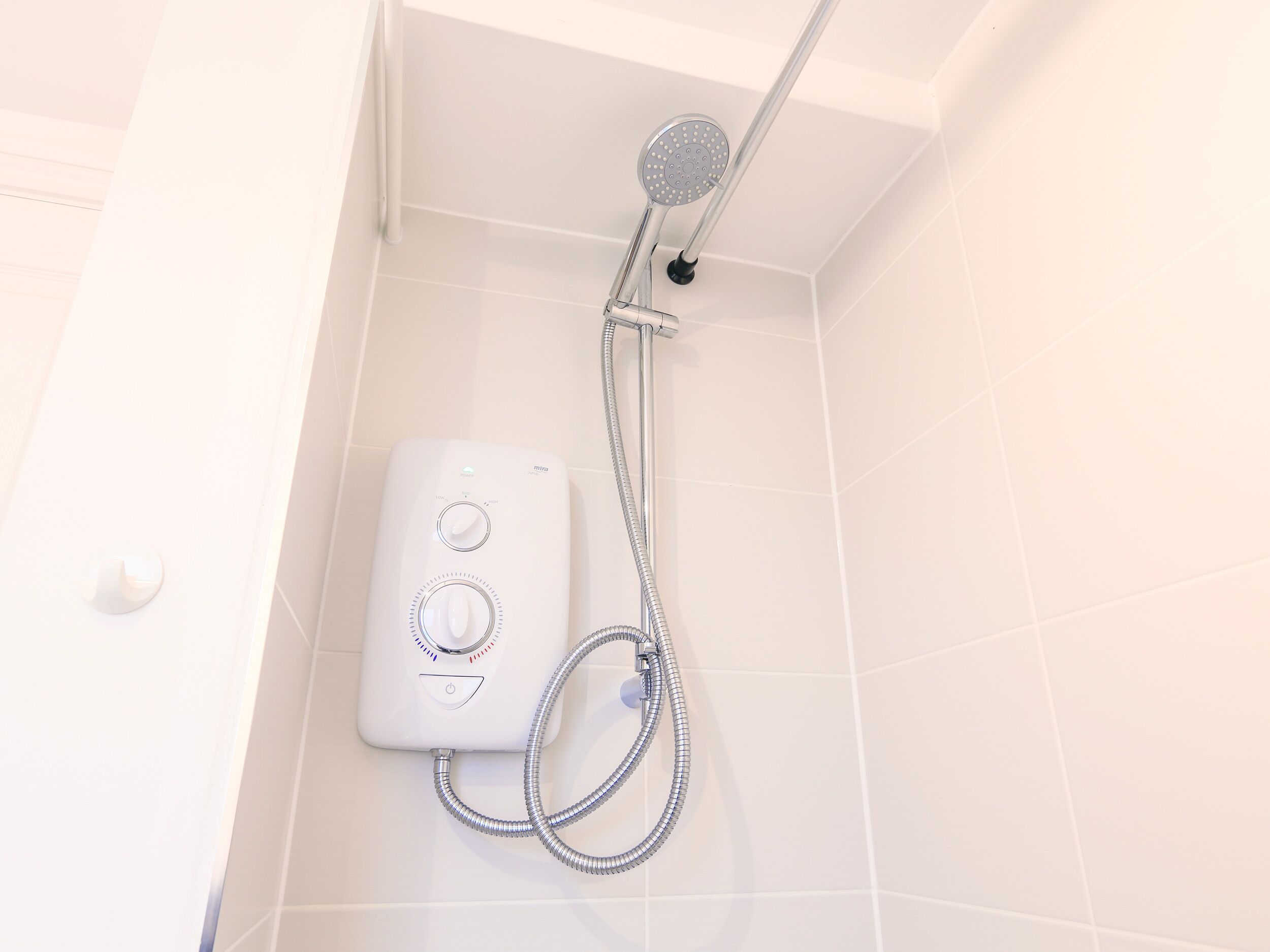 Una ducha con cabezal de ducha de mano y panel de control en la pared.