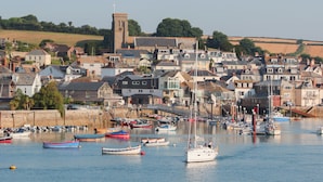 A coastal town with a prominent tower, a marina with various boats, and a densely packed residential area. - 2 North Crest House (Salcombe)