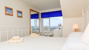 A hotel room with a bed, a chair, a desk with a lamp, and two framed pictures on the wall. - 2 North Crest House (Salcombe)