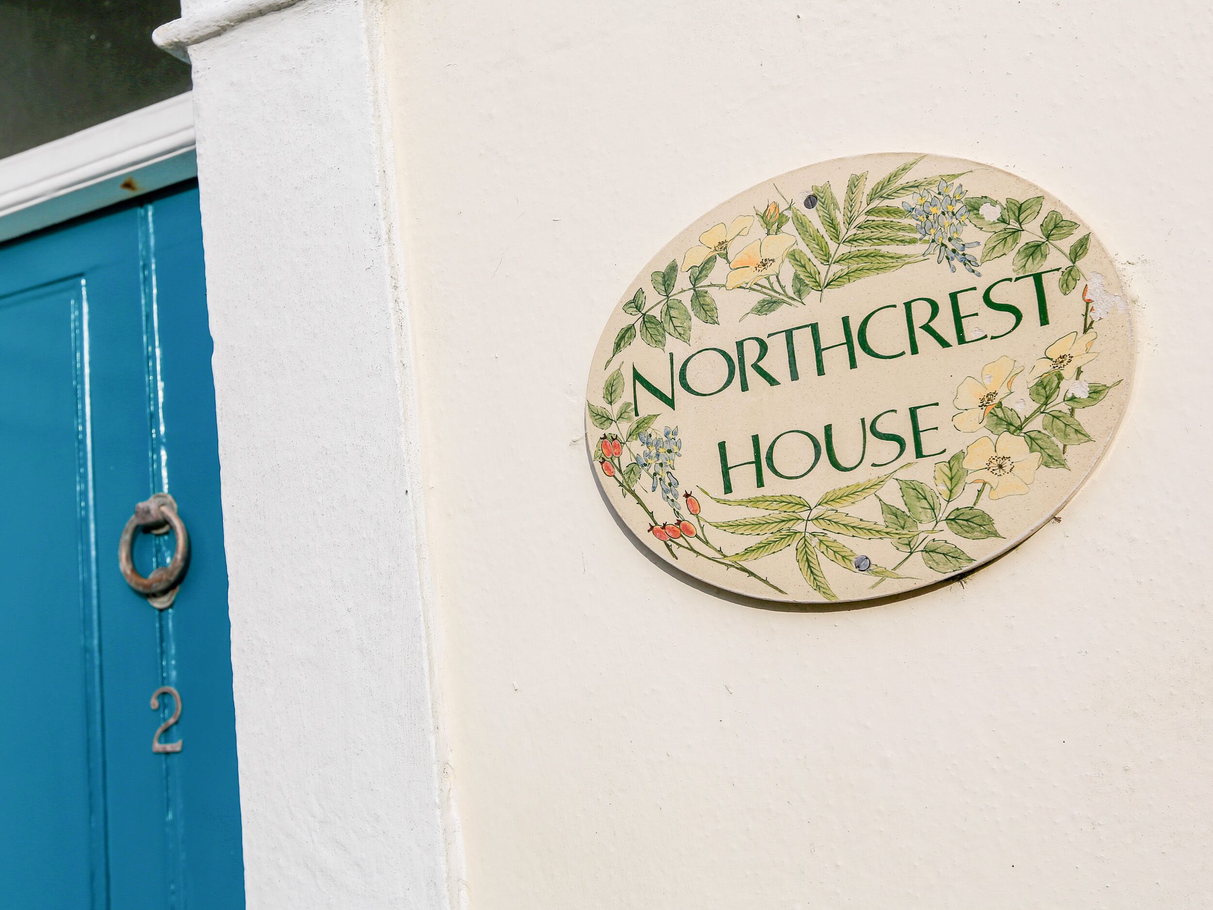 A house sign with the text "Northcrest House" surrounded by floral illustrations.