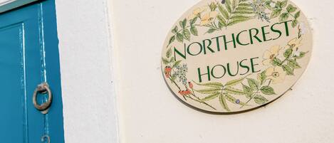 A house sign with the text "Northcrest House" surrounded by floral illustrations.