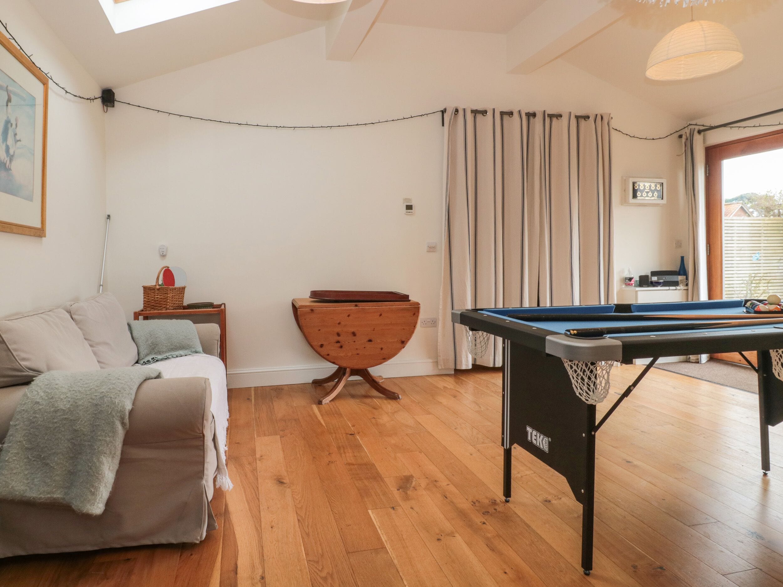 A cozy living room with a pool table, a sofa, and a wooden chair.