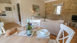 Un coin repas avec une table ronde dressée pour deux personnes, une bouteille de vin et une miche de pain.