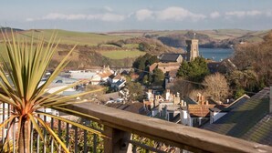 A coastal town with a prominent church tower, houses, and a body of water in the background. - Prospects (Salcombe)