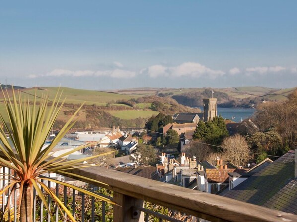 A coastal town with a prominent church tower, houses, and a body of water in the background. - Prospects (Salcombe)