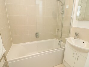 A bathroom with a bathtub, a glass shower enclosure, and a sink with a mirror above it. - Prospects (Salcombe)