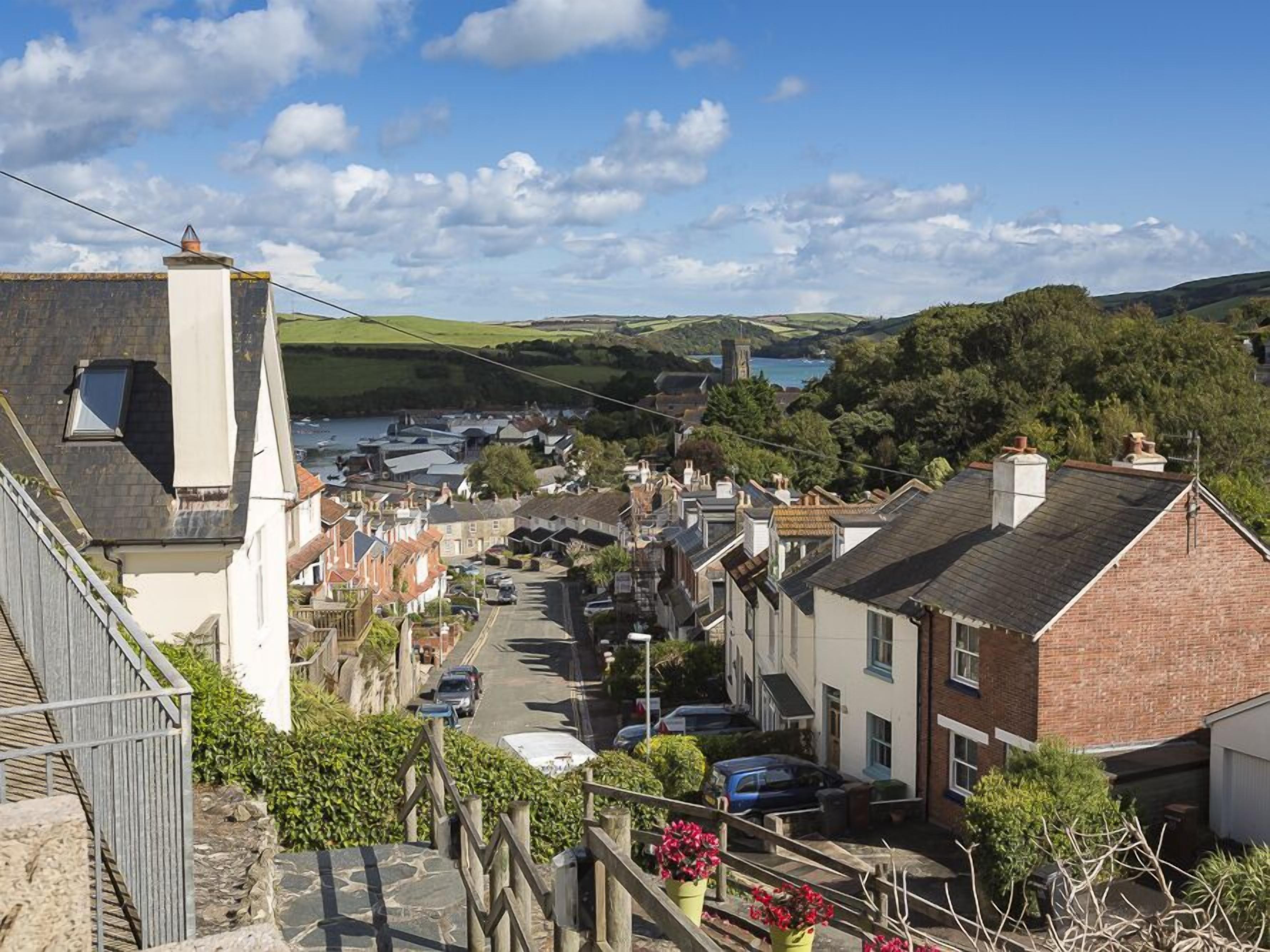 Une ville côtière avec des maisons à étages, une vue dégagée sur la mer et un clocher d’église imposant.