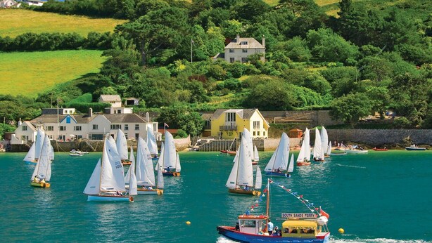 A coastal scene with sailboats on the water, a ferry, and houses on the hillside. - Prospects (Salcombe)