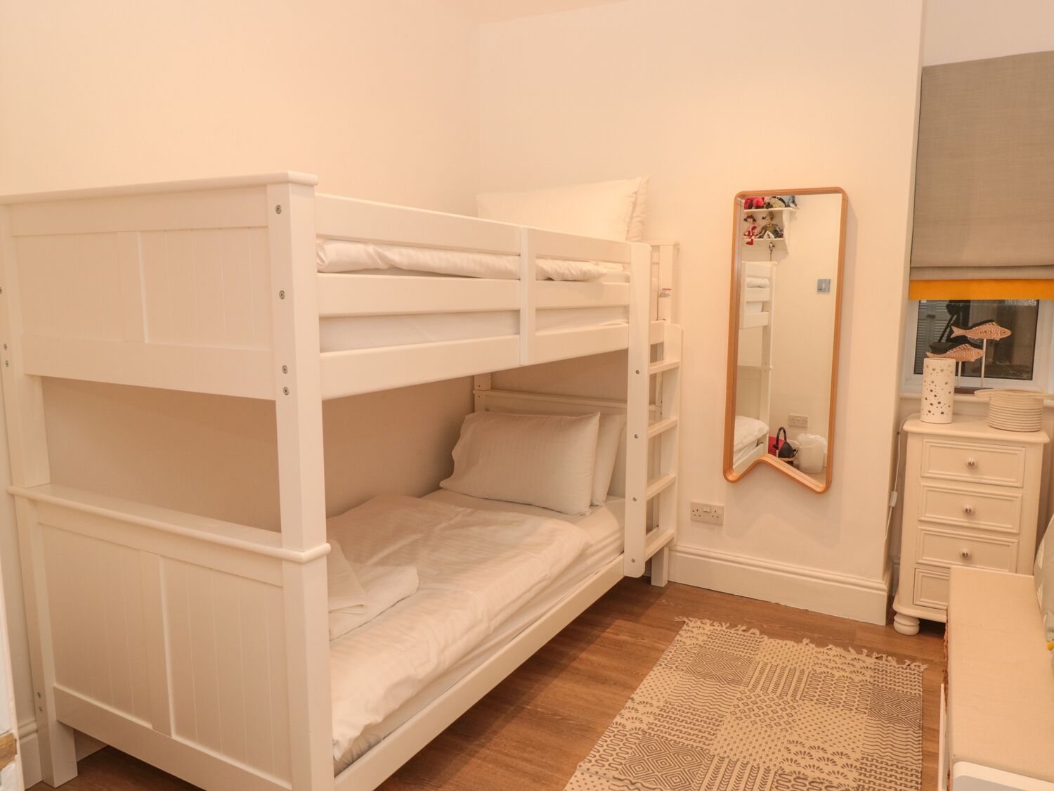 Habitación con literas, un espejo, cómoda y alfombra estampada.