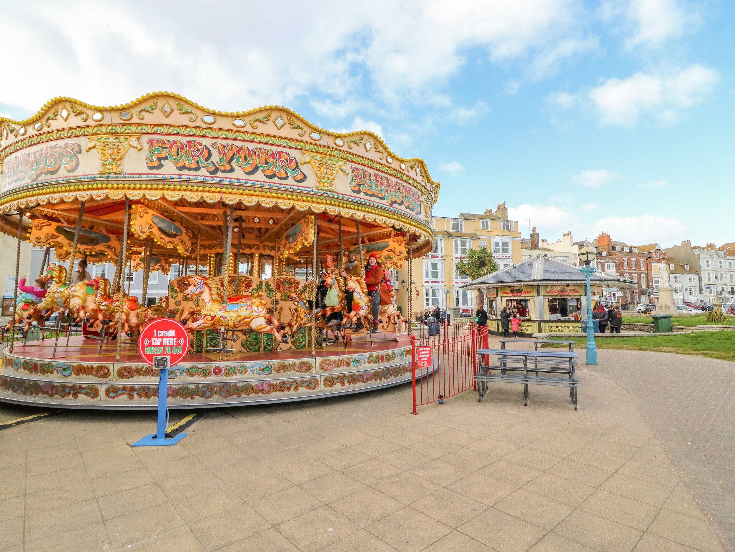 A carousel with colorful horses and a sign that reads "FOR YOUR".