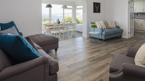 A modern living room with a grey sofa, a blue sofa, and a dining area with white chairs and a table. - Seaspray (Kingsbridge)