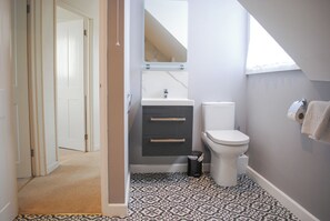 A bathroom with a toilet, sink, and patterned floor tiles. - Seagulls (Salcombe)