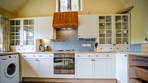 Une cuisine équipée d’un four encastré, d’un lave-linge et d’une fenêtre située au-dessus de l’évier.