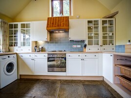 A kitchen with a built-in oven, a washing machine, and a window above the sink.