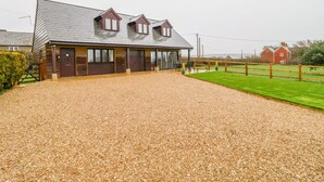 A stable with a gravel driveway and a fenced yard. - The Donkey Shed (Sherborne)