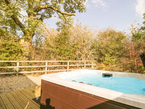 A hot tub on a wooden deck surrounded by trees.