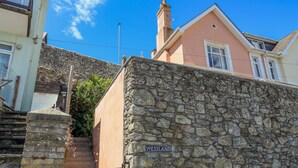 A stone wall with a sign reading "WESTLAND" and a staircase leading up to a building. - Westland (Salcombe)
