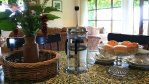 Una mesa de comedor con una jarra de vidrio, una cesta de mimbre y un arreglo floral.