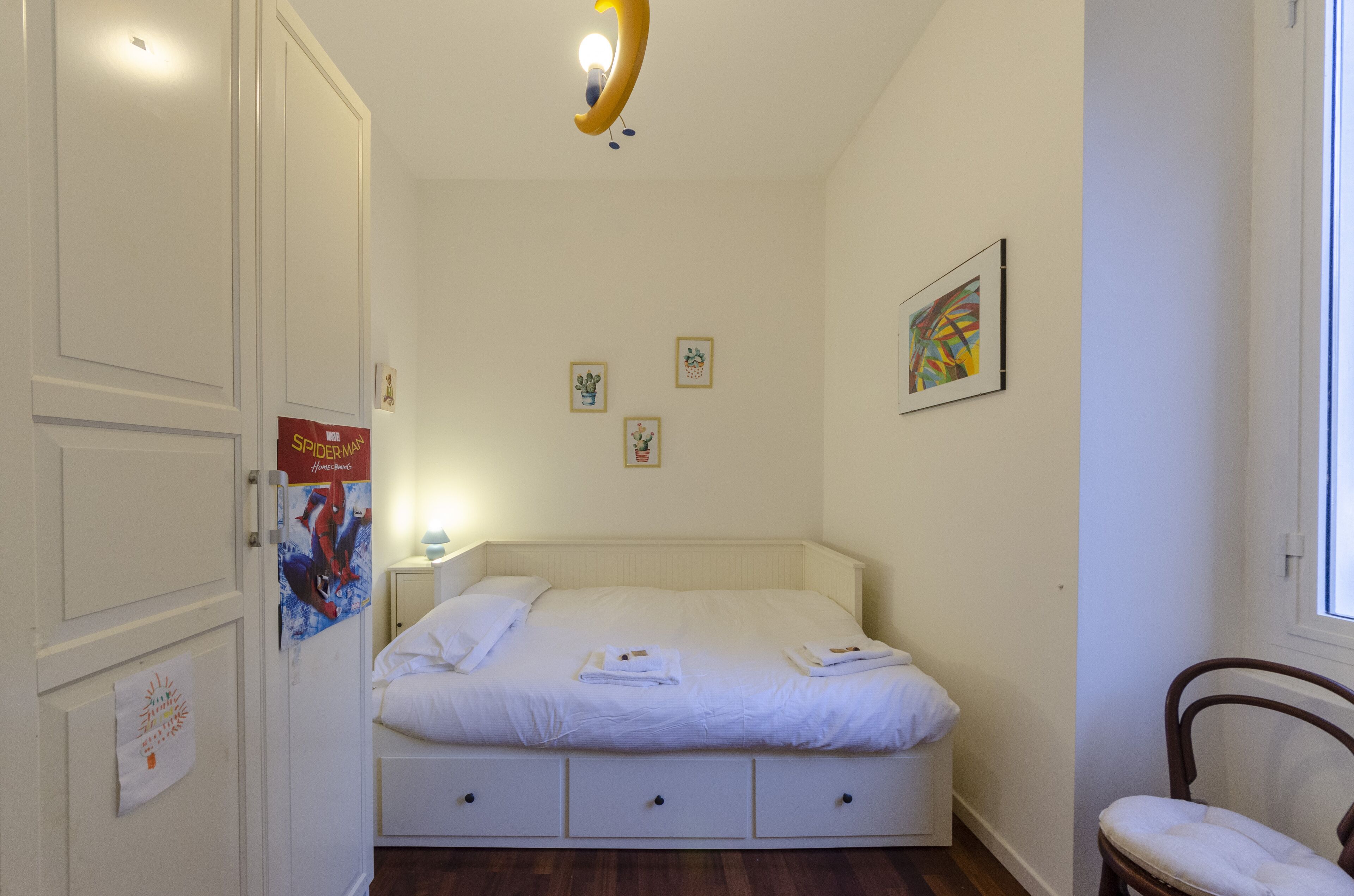 Um quarto com uma cama, uma cadeira e uma porta.