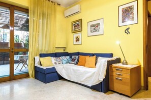 A room with a blue sofa, yellow curtains, a wooden cabinet, and a table with a tablecloth.