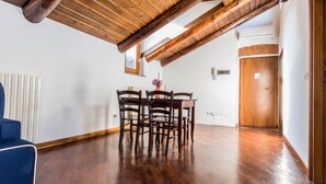 A dining area with a wooden table and chairs, a radiator, and a wooden door. - JOIVY Big Wooden Apartment for 6 near Milano Center (Milan)