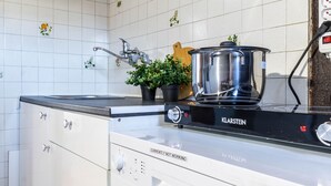 A kitchen with white cabinets, a black countertop, and a Kalarstein electric stove. - JOIVY Big Wooden Apartment for 6 near Milano Center (Milan)