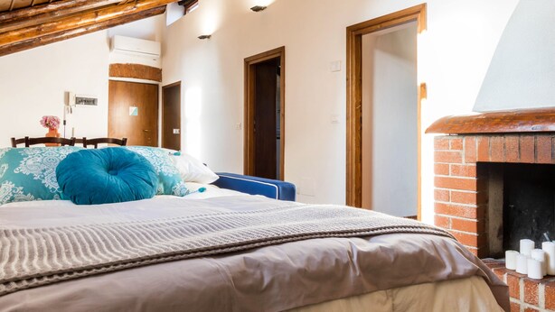 A bedroom with a bed, a brick fireplace, and wooden doors. - JOIVY Big Wooden Apartment for 6 near Milano Center (Milan)