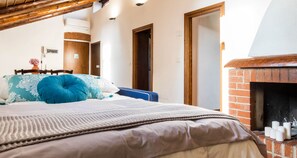 Une chambre à coucher avec un lit, une cheminée en briques et des portes en bois.