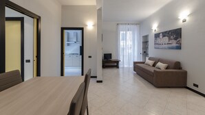 A modern living room with a dining area, a sofa, and a painting on the wall. - JOIVY Monte Suello (Genoa)