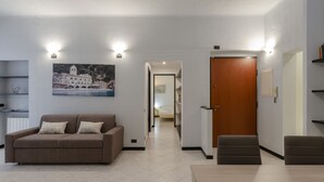 A modern living room with a sofa, a dining table, and a wooden door. - JOIVY Monte Suello (Genoa)