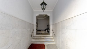 A staircase with white marble walls and a patterned floor, leading to a landing area. - JOIVY Monte Suello (Genoa)