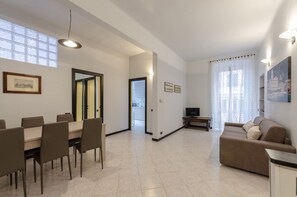 A spacious living area with a dining table, sofa, and a TV. - JOIVY Monte Suello (Genoa)