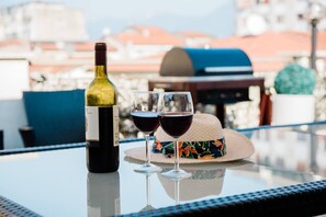 A bottle of wine and two glasses on a glass table with a city view in the background. - JOIVY Elly's Terrace-old City (Viareggio)