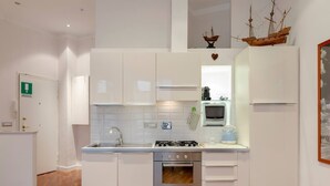 Una cocina moderna con armarios blancos, una estufa a gas, horno empotrado y microondas.