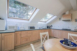Una cocina con armarios de madera, microondas, tostadora y una mesa de comedor con un tazón azul.
