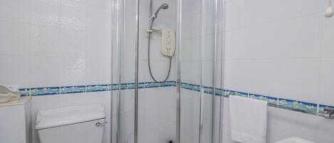 A bathroom with a glass-enclosed shower, a toilet, and a sink.