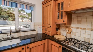 Una cucina con mobili in legno, un piano cottura a gas, un lavello e una finestra con vista sugli edifici.