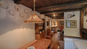 Een rustieke eetruimte met een houten tafel, stoelen en een bloemenkronkel als hanglamp.