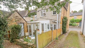 A house with a conservatory, stone walls, and a wooden fence. - Newbury Cottage (Cheltenham)