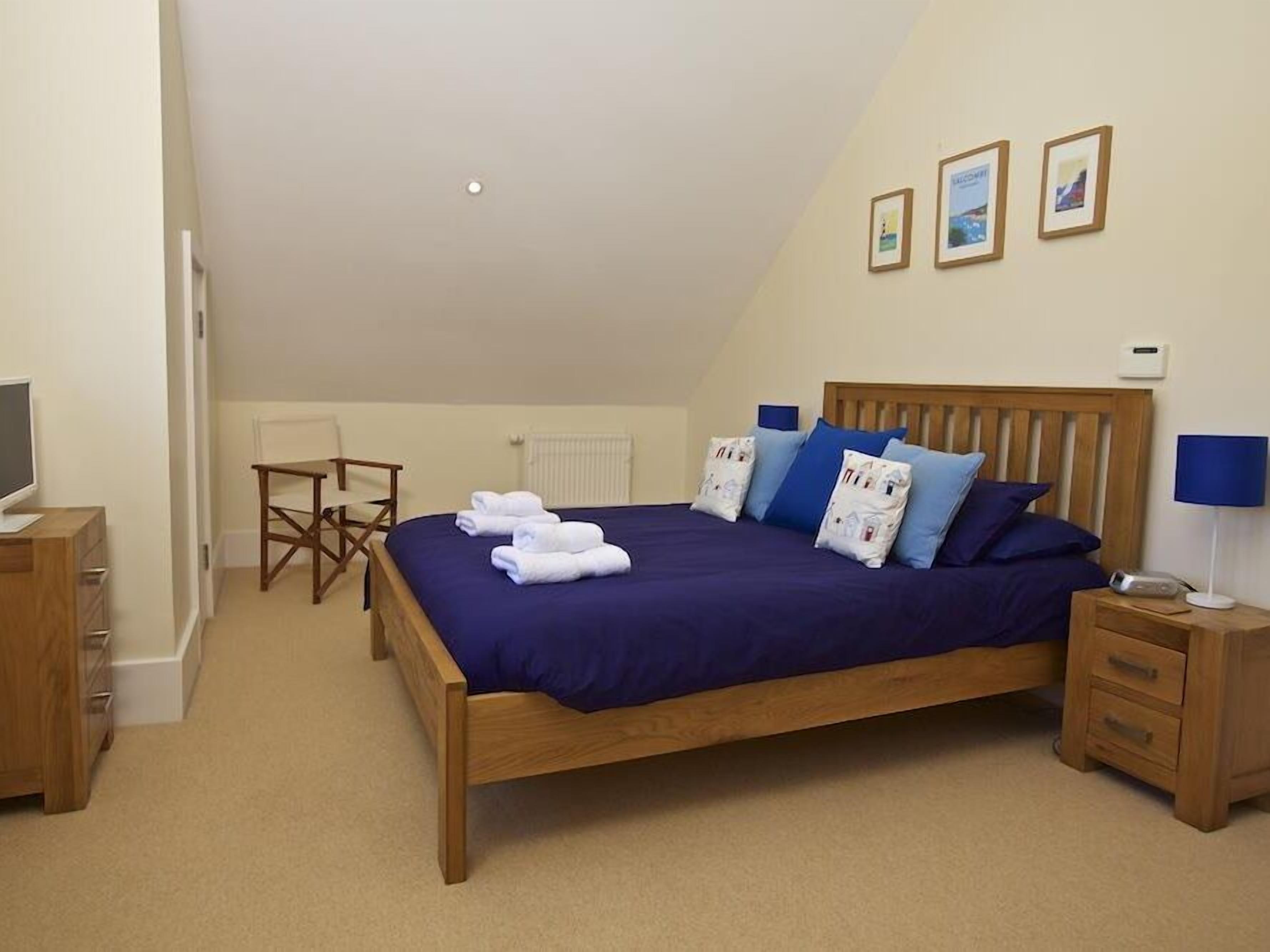 A bedroom with a wooden bed, a desk, a chair, and a TV.