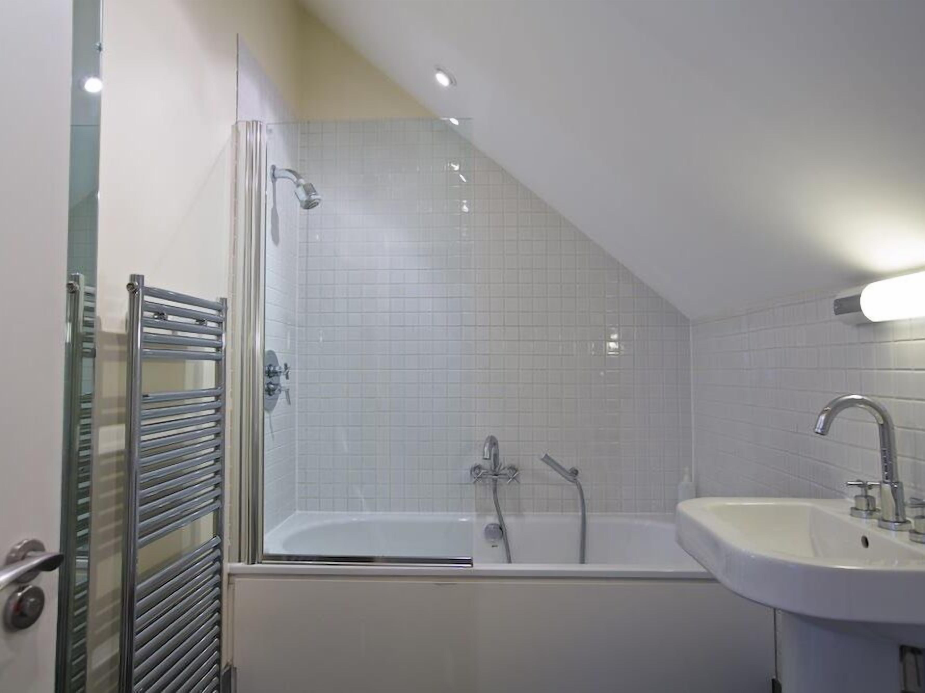 A modern bathroom with a glass-enclosed shower, a freestanding bathtub, and a sink.