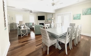 A spacious living room with a dining area, hardwood floors, and a ceiling fan.